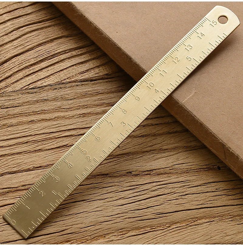 Messlatte in Form eines goldenen Dreiecks diagonal auf einer Holzoberfläche.