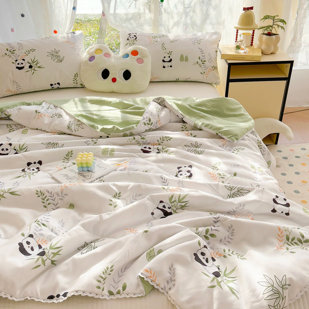 White comforter featuring a panda print pattern and lace trim, displayed on a bed with green accents.
