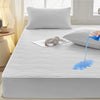 A white fitted mattress protector is shown with blue water dripping onto the surface.