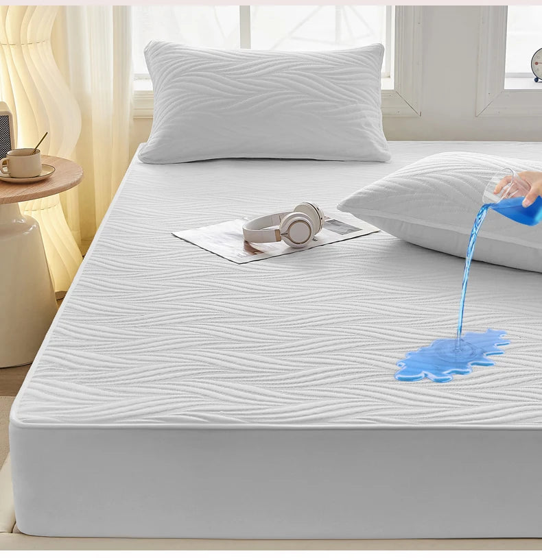 A white fitted mattress protector is shown with blue water dripping onto the surface.