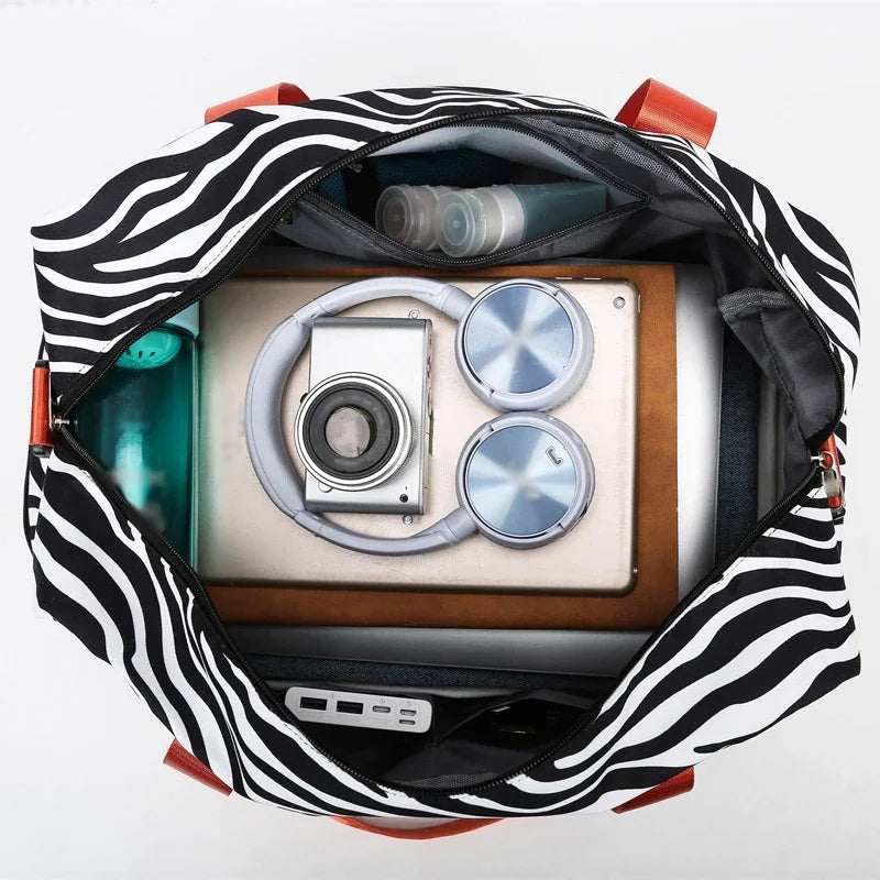 Black and white zebra print duffle bag open showing a camera and other gear inside