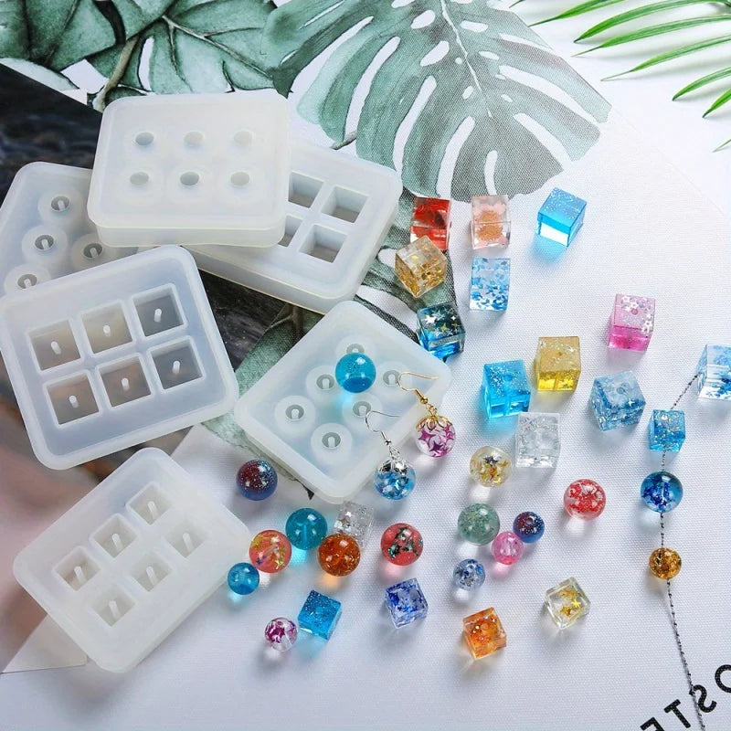 White silicone molds filled with colorful crystal ball beads and various gemstone shapes on a white background.