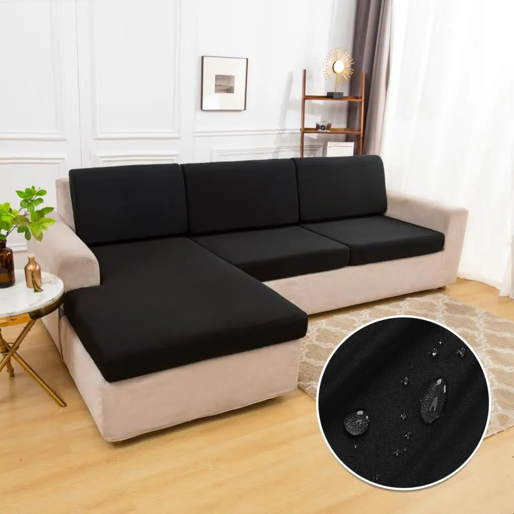 A black waterproof sofa cushion cover with an elastic edge displayed on a beige sofa.