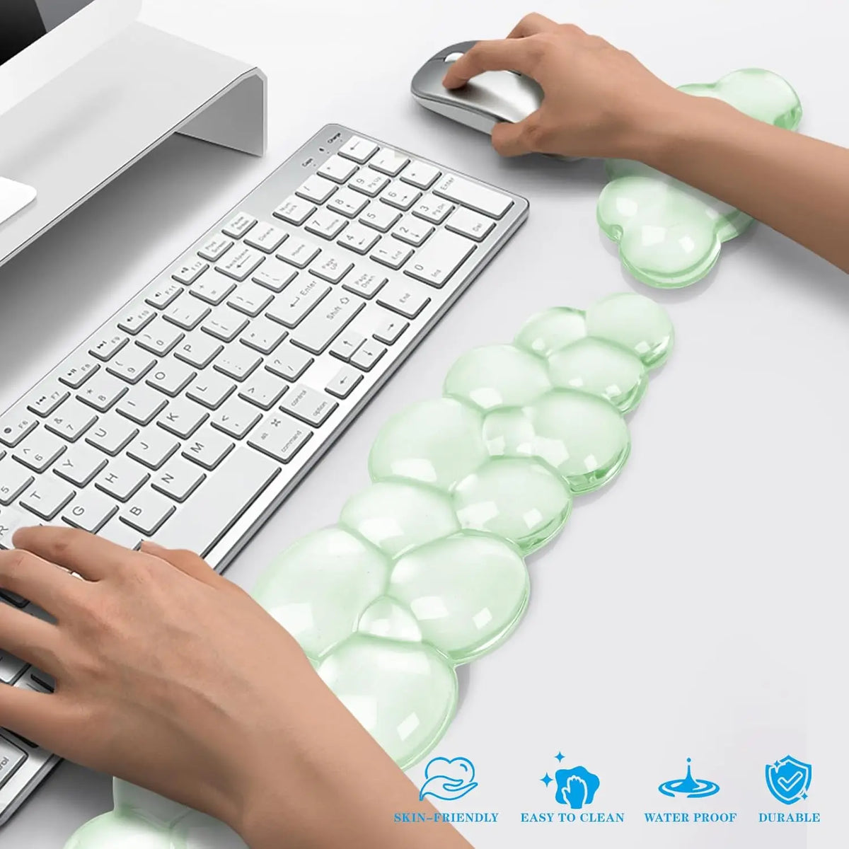 A set of translucent green cloud-shaped ergonomic wrist rests for a keyboard and mouse are shown next to a laptop.