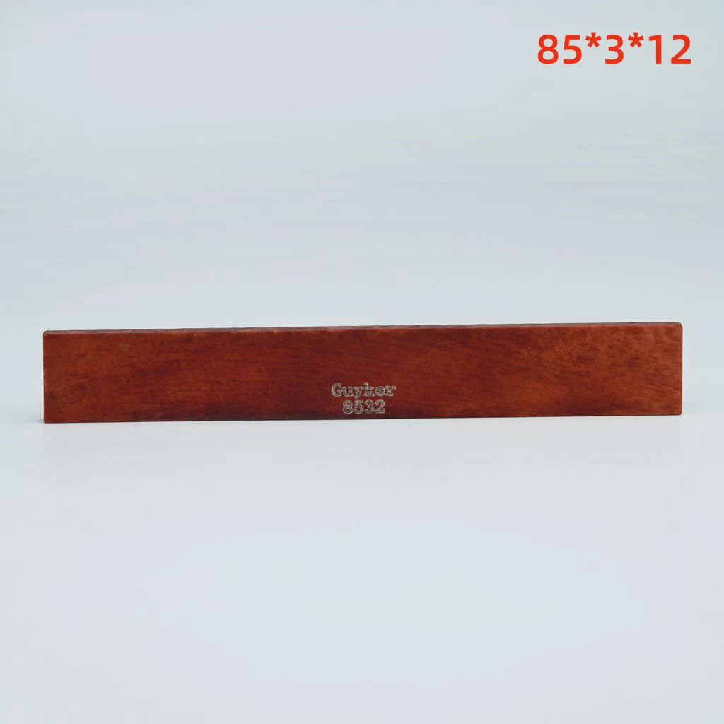 A rectangular piece of brown leather used as an acoustic guitar bridge saddle.