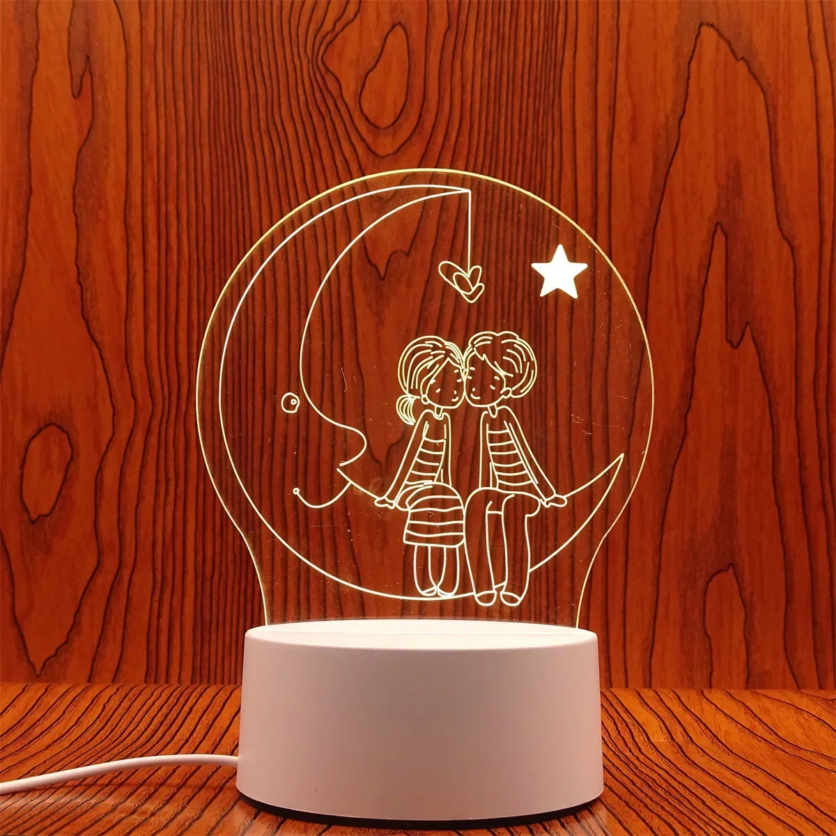 A white line drawing of a couple silhouette inside a crescent moon on a light pink lamp base.