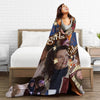 A woman is lying on a bed with a large throw blanket featuring Gilmore Girls characters and themes.