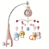 A pink musical baby crib mobile featuring a crown, a light projector, and various animal charms.