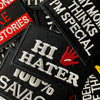 A close-up of black embroidered iron-on patches featuring text like HI HATER and 100% SAVAGE.