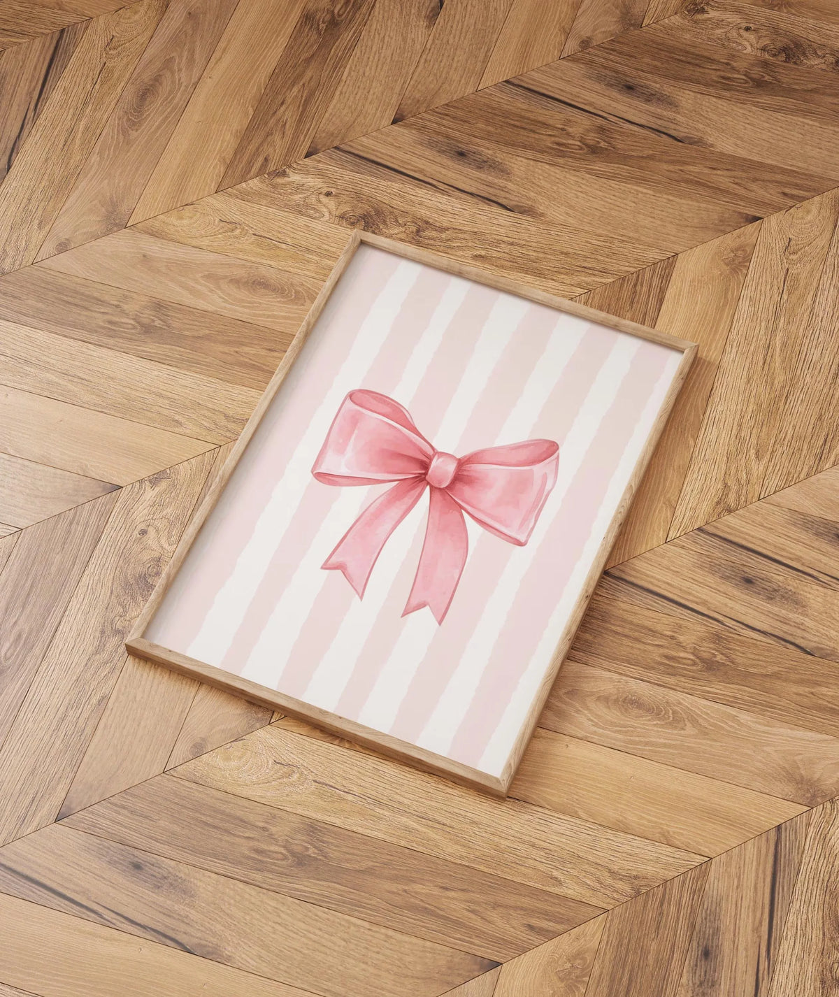 A framed canvas print featuring pink striped background and a pink bow on a wooden floor.