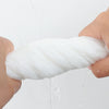 Una mano aprieta una toalla facial desechable blanca y gruesa, con agua goteando.