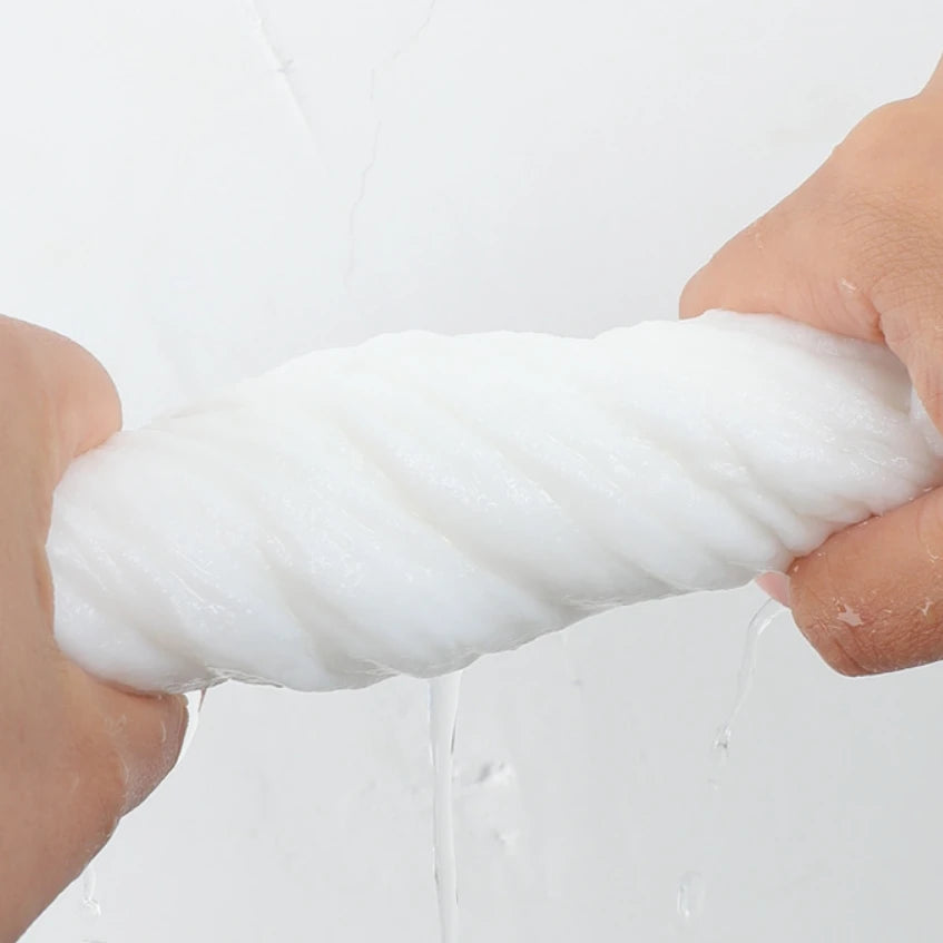 Una mano aprieta una toalla facial desechable blanca y gruesa, con agua goteando.