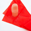 A pink thumb tip product resting on a red silk cloth.