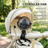 A white stroller fan with a black blade is mounted on a flexible tripod stand in an outdoor setting.