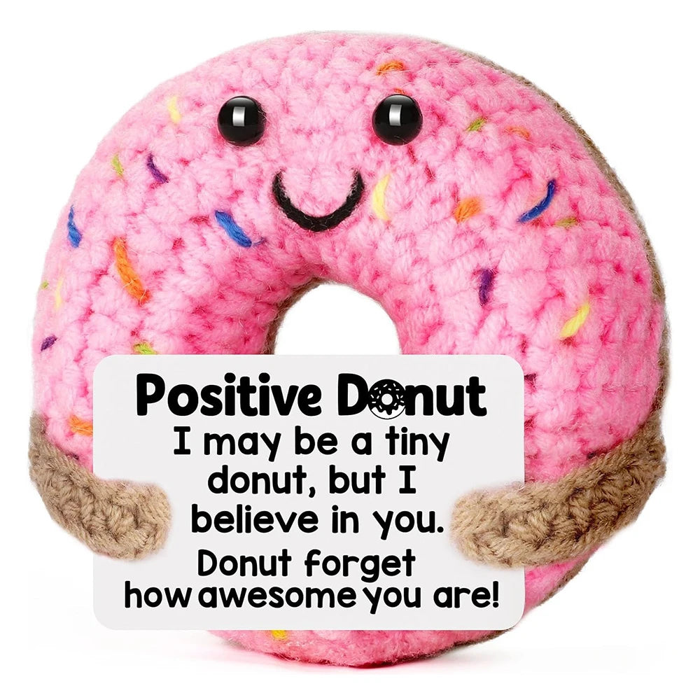 A pink donut shaped plush ornament with a smiling face and text encouraging positivity.