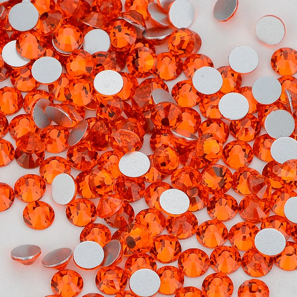 A close-up view of multi-color glitter round glass flatback rhinestones in shades of orange and silver.