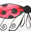 A red ladybug wing costume featuring black polka dots and swirling black lines.