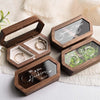 A set of personalized engraved walnut wood ring boxes with black velvet pouches for wedding rings.
