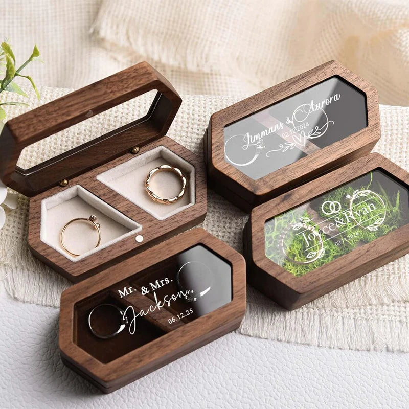 A set of personalized engraved walnut wood ring boxes with black velvet pouches for wedding rings.
