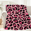 A pink and black leopard print flannel throw blanket draped over a light-colored sofa.