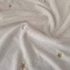 A close-up of a white coral fleece baby blanket with subtle gold star and crescent moon embroidery.