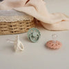 A silicone baby pacifier in pale pink and mint green colors resting on a white surface.