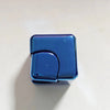 A small, rectangular blue metal fidget spinner cube resting on a white surface.