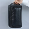 A hand is holding a black PU vintage luxury toiletry bag.