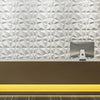 A modern reception desk in a bright office featuring a textured white diamond wall panel and a glowing yellow base.