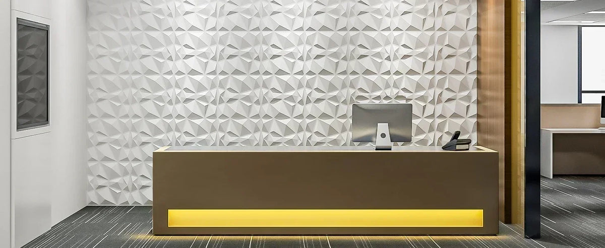 A modern reception desk in a bright office featuring a textured white diamond wall panel and a glowing yellow base.