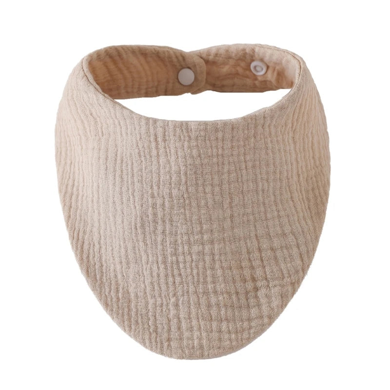A beige organic cotton muslin baby bib with an absorbent band around the neck.