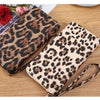 A pair of leopard print retro long wallets, one dark brown and one beige, resting on a wooden surface.