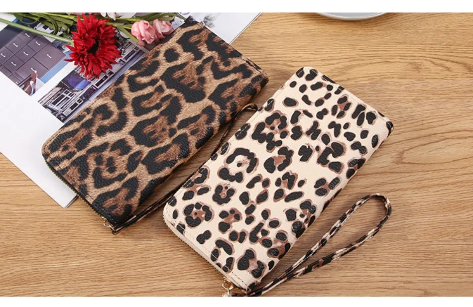 A pair of leopard print retro long wallets, one dark brown and one beige, resting on a wooden surface.
