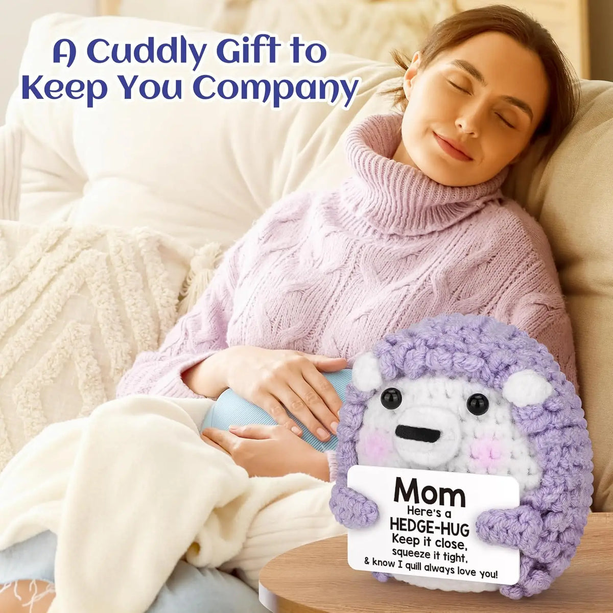 A handmade crochet purple hedgehog doll with an inspirational card resting on a person's lap.