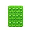 A green silicone suction pad with multiple circular indentations for phone mounts.