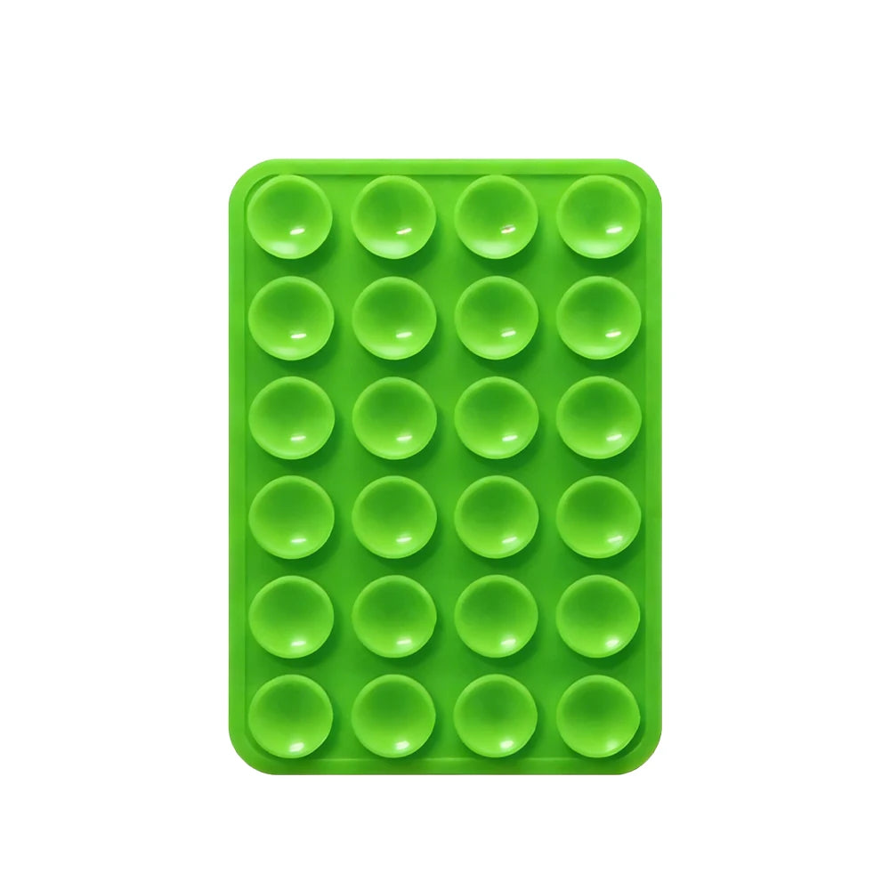 A green silicone suction pad with multiple circular indentations for phone mounts.