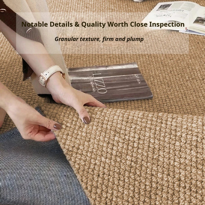 A close-up of a brown faux sisal non-slip kitchen runner rug on a beige carpet, with a hand touching the texture.