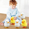 A child is sitting with several yellow and white wind-up walking chicken toys on the floor.