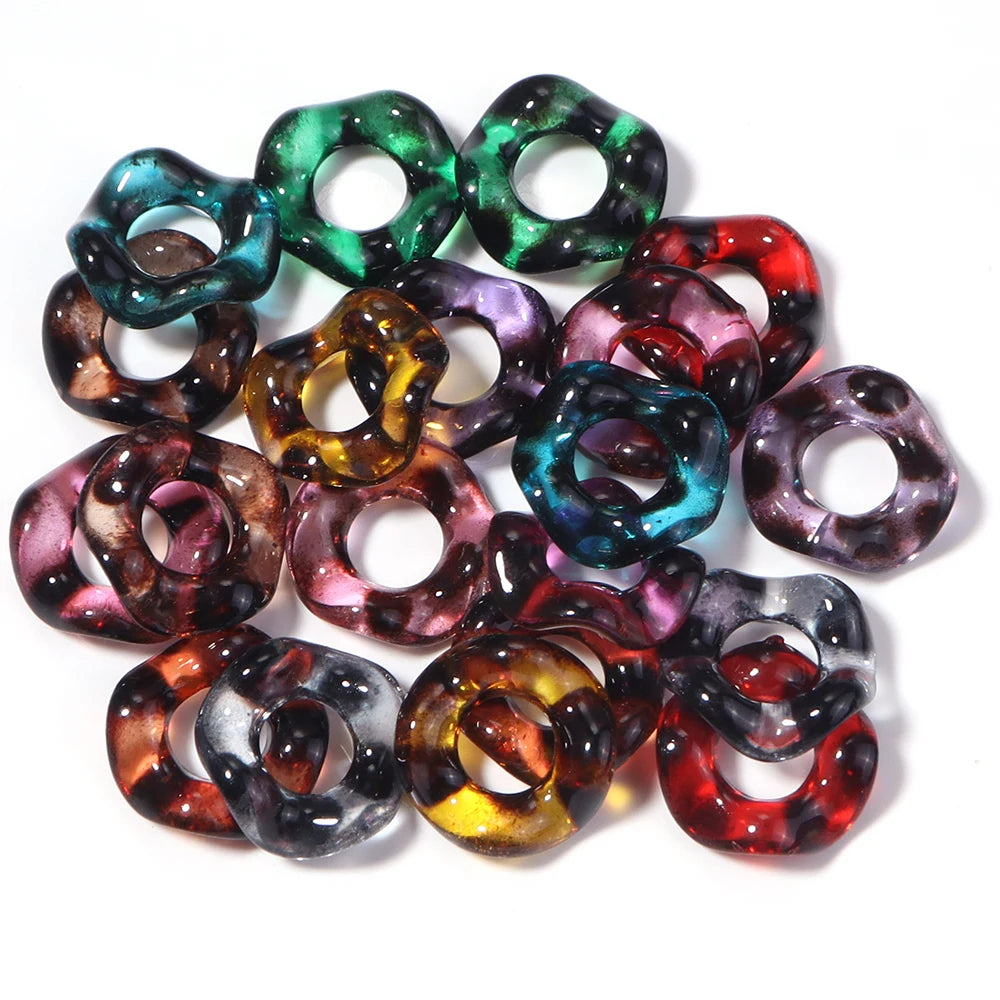 A collection of colorful acrylic spacer beads in wave patterns, including green, purple, and red shades.