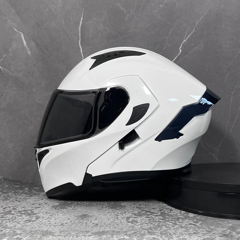 A white modular flip-up motorcycle helmet is displayed on a gray surface.