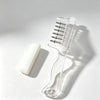 Clear refillable scalp massage comb with roller ball applicator resting on a white surface.