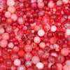 A close-up view of mixed sized glass beads in shades of pink and red.