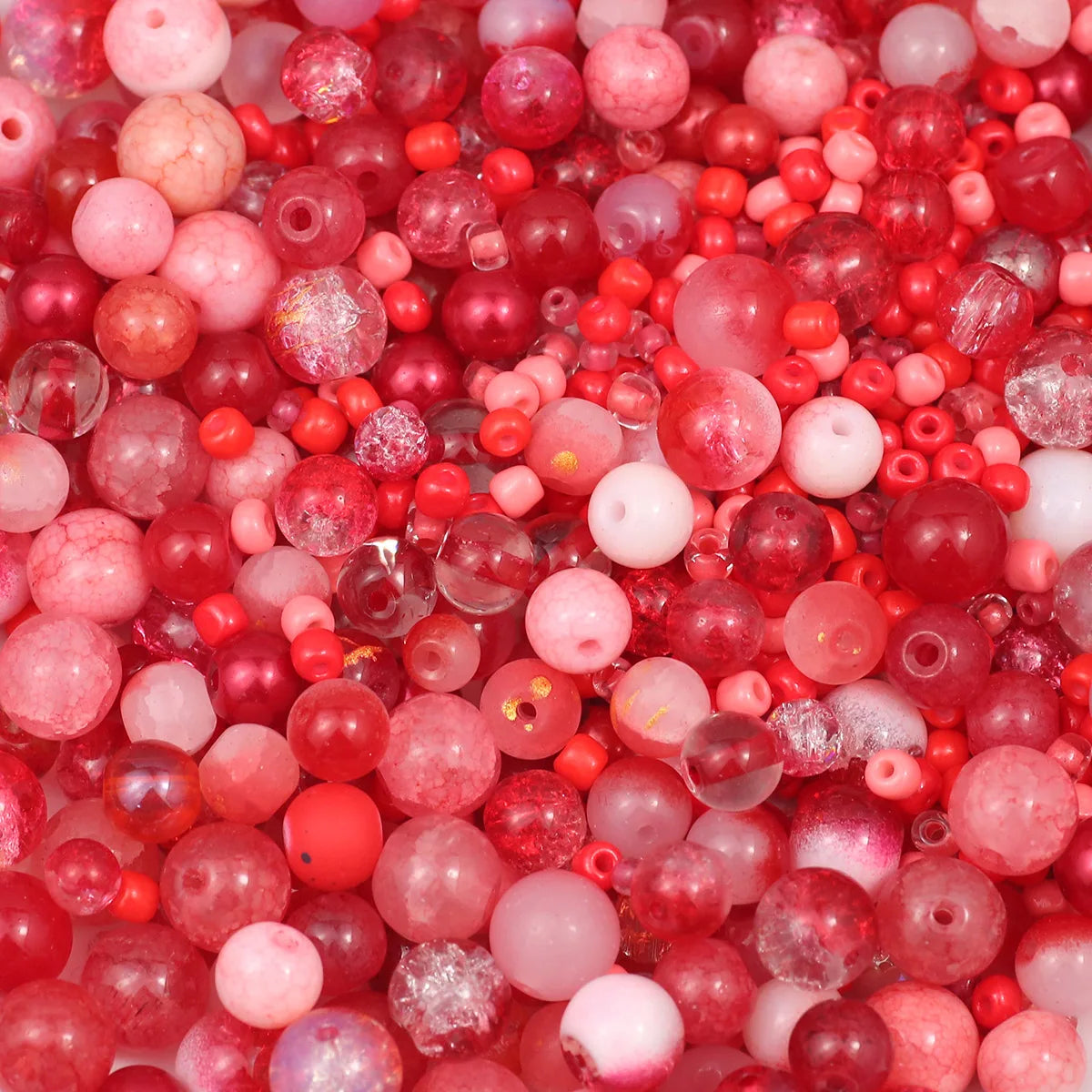 A close-up view of mixed sized glass beads in shades of pink and red.