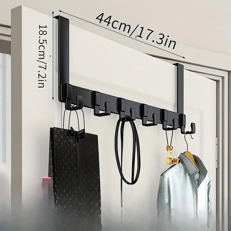 A black over-the-door coat rack with six hooks is shown mounted on a white door, demonstrating its 44cm length.