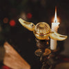 Golden snitch angel wings metal fidget spinner resting on a candle