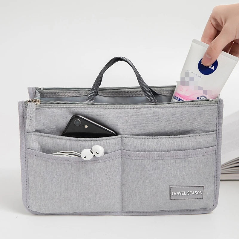 A gray purse organizer insert with multiple compartments is shown, holding a smartphone and earbuds.