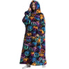 A woman wearing an oversized wearable blanket hoodie with sleeves featuring a Halloween pumpkin print.