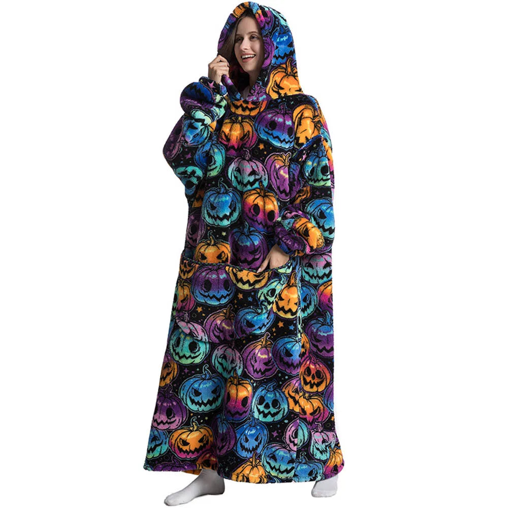 A woman wearing an oversized wearable blanket hoodie with sleeves featuring a Halloween pumpkin print.