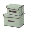 A set of two rectangular fabric storage boxes in a light sage green color with dark gray trim.