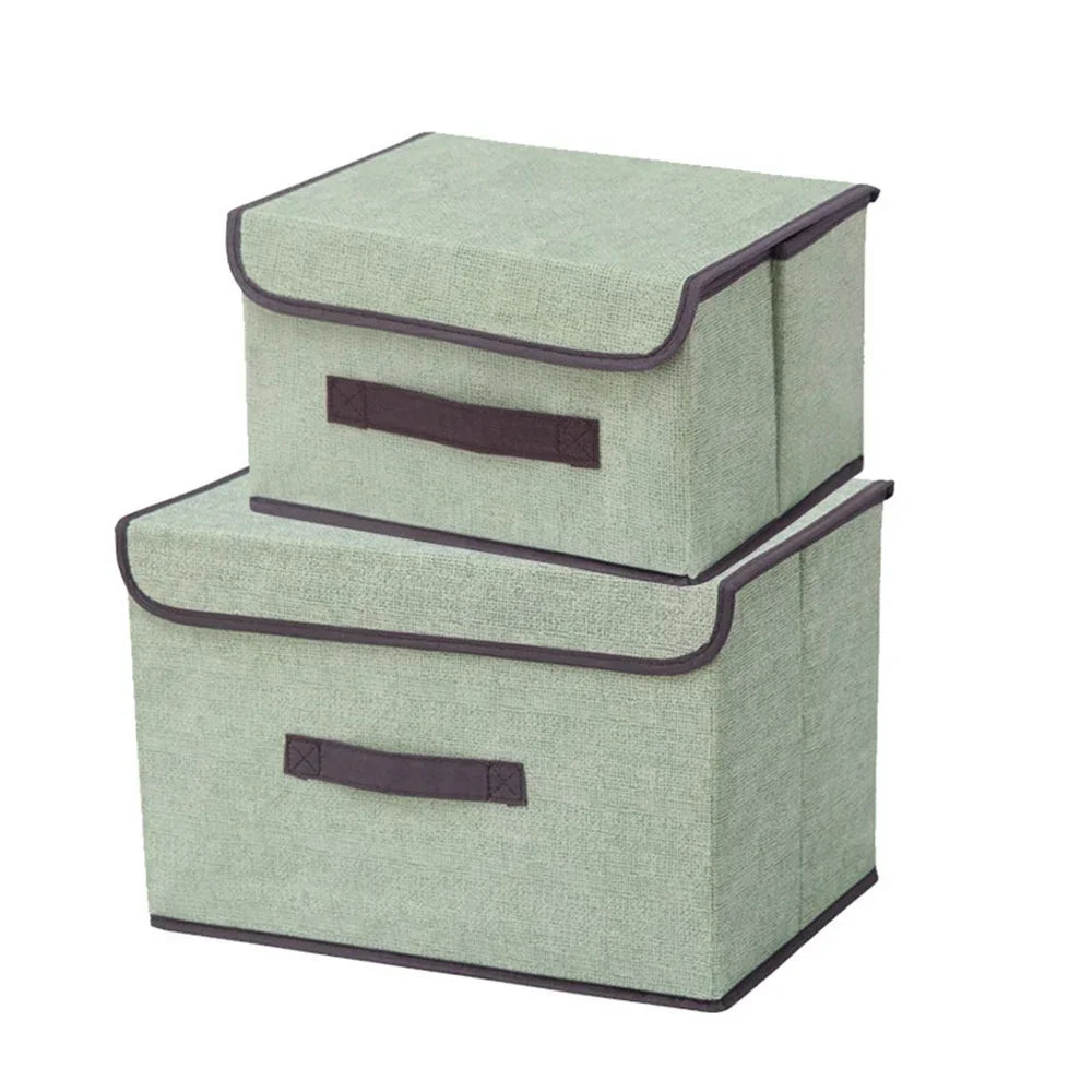 A set of two rectangular fabric storage boxes in a light sage green color with dark gray trim.
